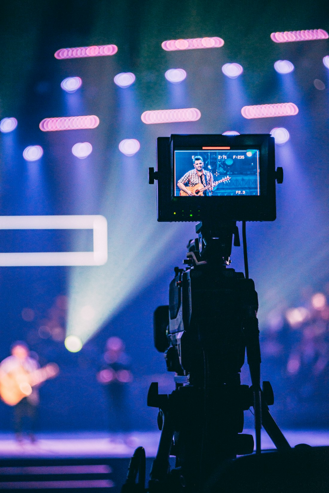 A broadcast camera operator framing a main-stage act
